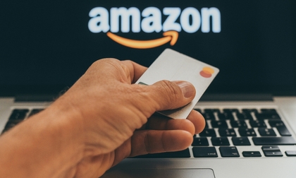 man holding a credit card in front of Amazon website