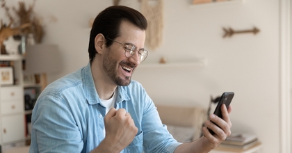Overjoyed man wearing glasses holding smartphone
