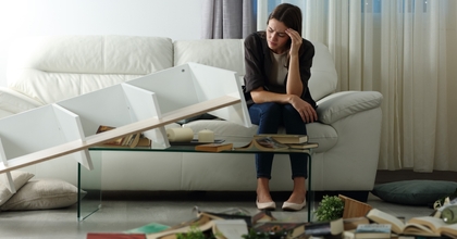 Upset woman sitting on a couch in ransacked living room