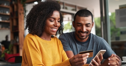 man looking at his girlfriend shopping online in cafe