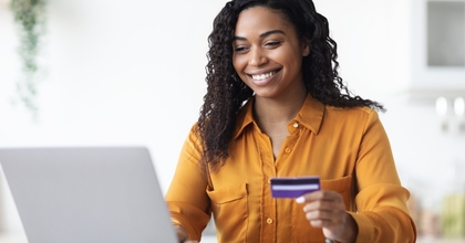Woman looking at computer holding a credit card