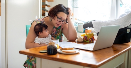 Woman holding baby and looking at computer