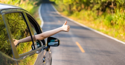 A driver on a two-lane road gives a thumbs up.