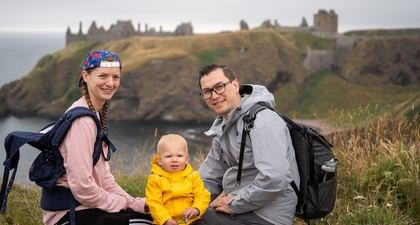 The author with his wife and young son, shown sitting on a bluff overlooking a Scottish castle. They are looking at the camera and smiling.