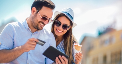 Smiling couple using a credit card on a tablet