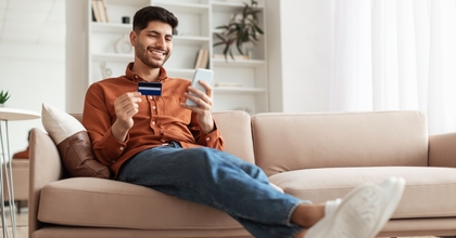Smiling man looking at his credit card and phone