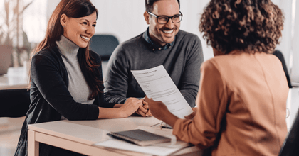 A couple holds hands and talks with a bank manager. 
