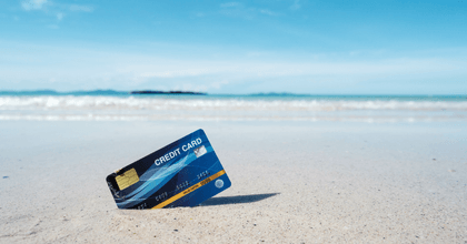 A credit card stuck in the sand on a beach.