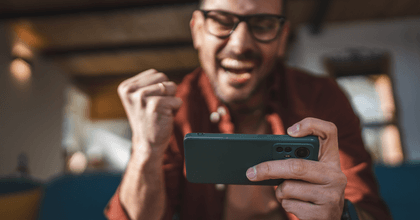 A man cheers while playing a game on his phone.