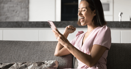 A woman smiles while using her phone.