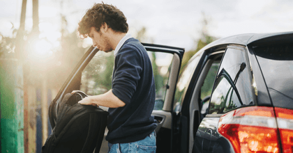teen with backpack standing outside car