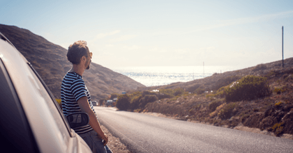 person leaning against car by side of road