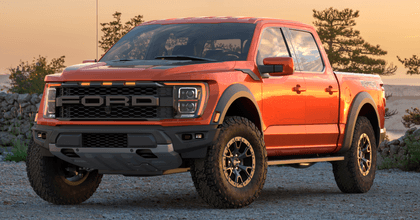 A new orange Ford F-150 Raptor is shown in a parking lot.
