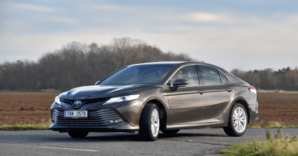 A man drives a dark gray Toyota Camry. 