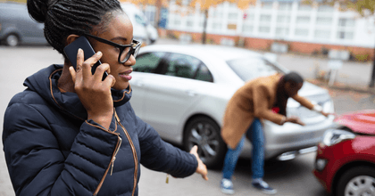 A woman makes a phone call after being in a car accident.