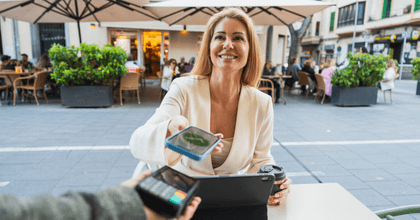 A woman smiles while using her phone to make a payment.
