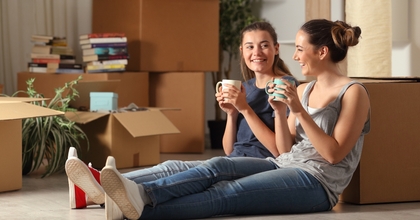 Young women sitting on floor of new home drinking coffee
