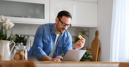 Man with credit card searching on laptop