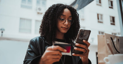 teenager with shopping bag on phone holding credit card