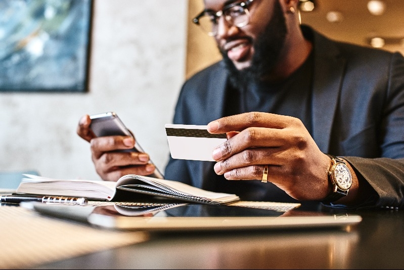 Black man on phone using credit card