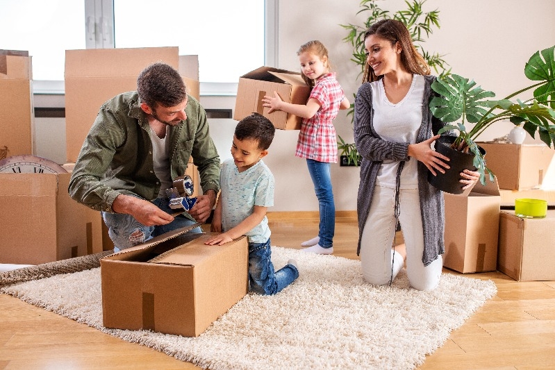 Young couple moving intp a new home with their children helping