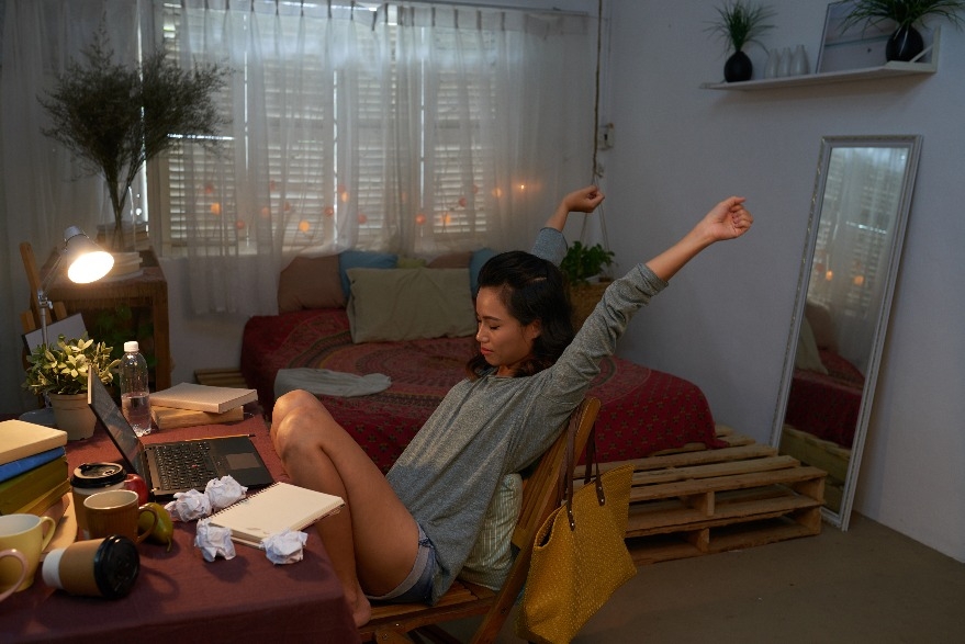 Woman stretching at desk in dorm room