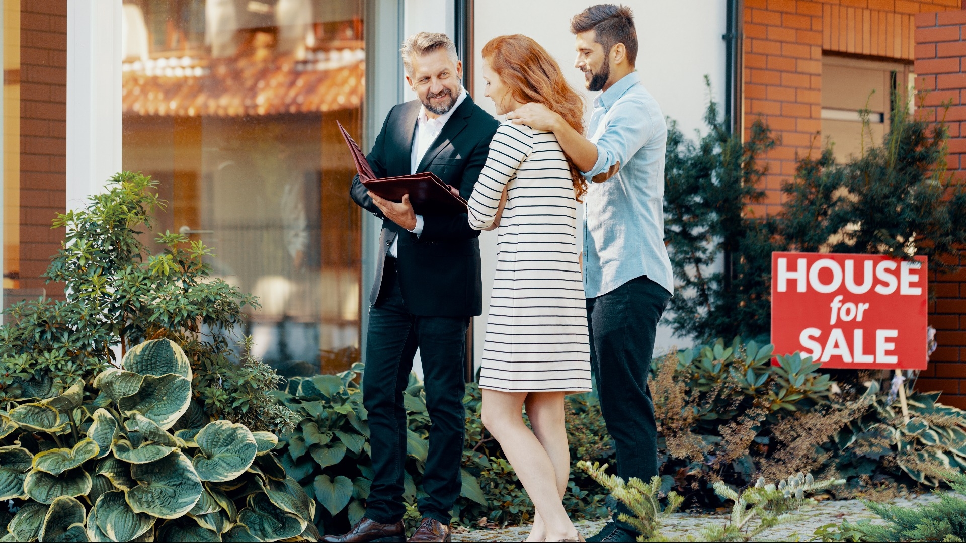 Smiling businessman with loan contract talking with house buyers 