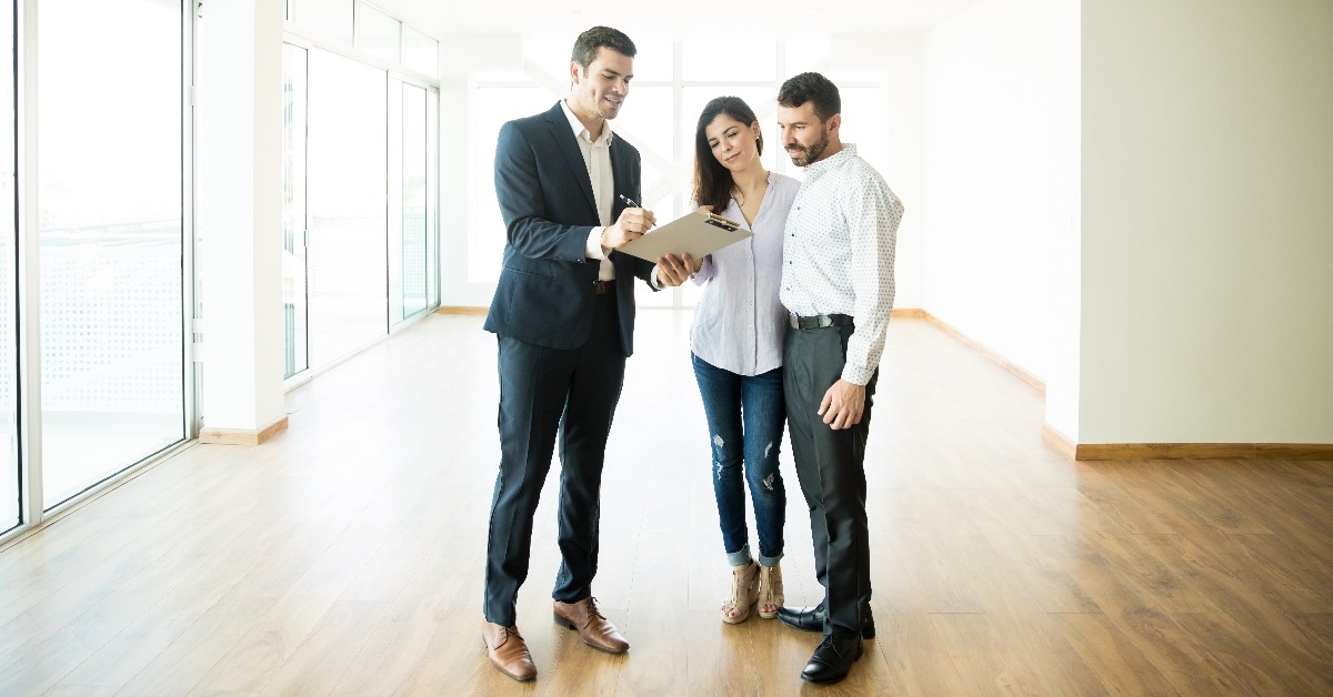 Realtor Explaining Agreement To Couple In New Apartment 