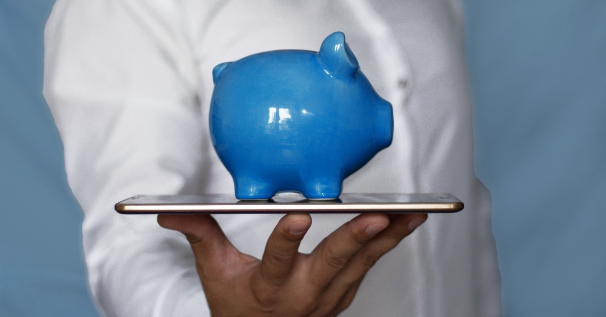 Hand holding piggy bank and iPad