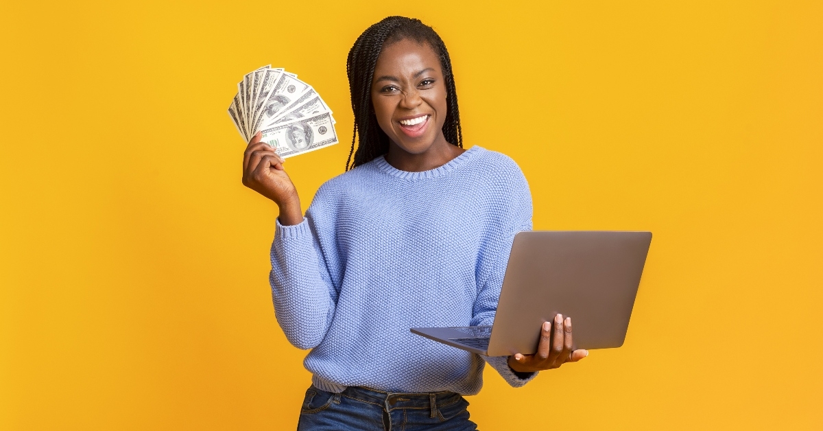 Happy woman holding money and laptop