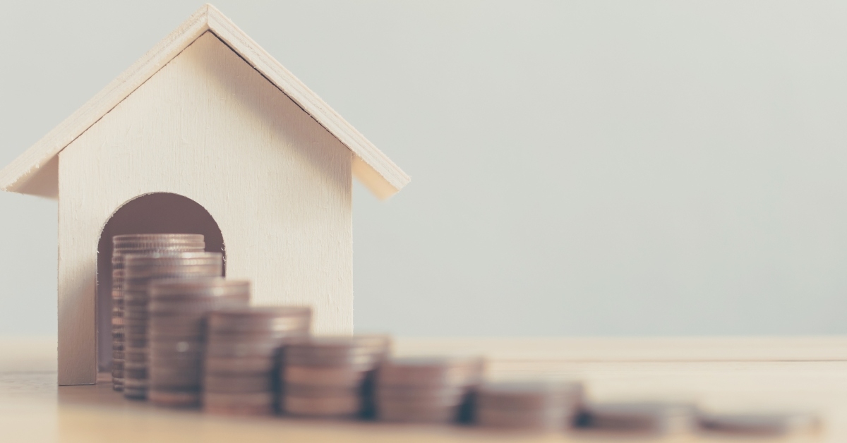 Tiny wooden house with coins stacked in front