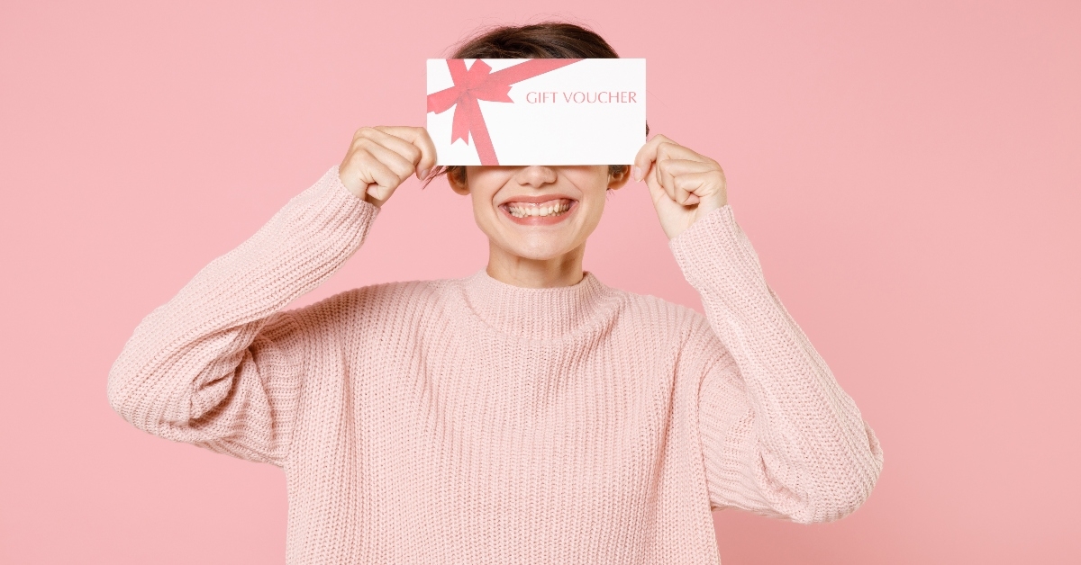 Smiling person holding gift voucher over eyes