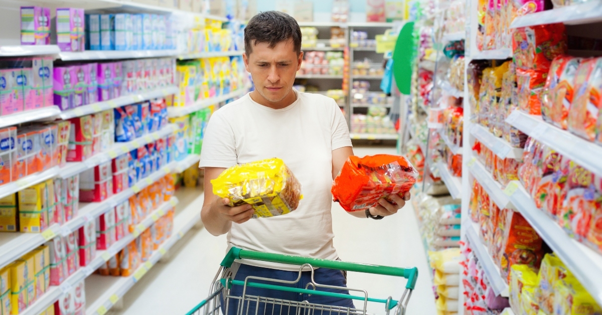 Man comparing two products at the grocery store