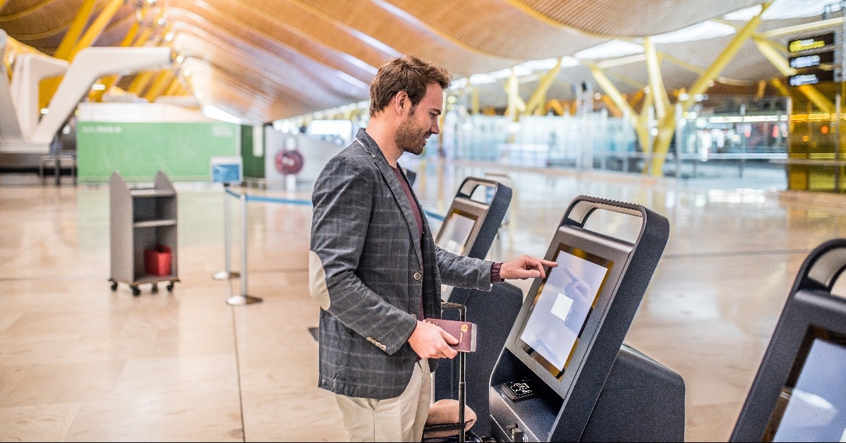 happy man using the check-in machine at the airport getting the boarding pass