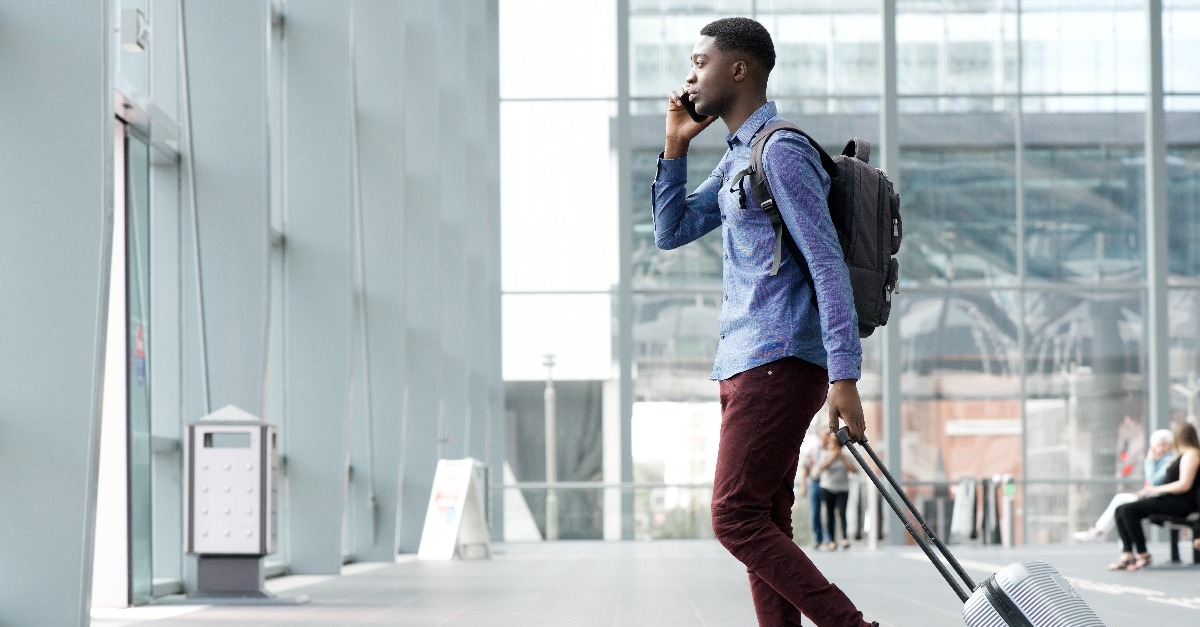 man traveling with suitcase and cellphone at airport