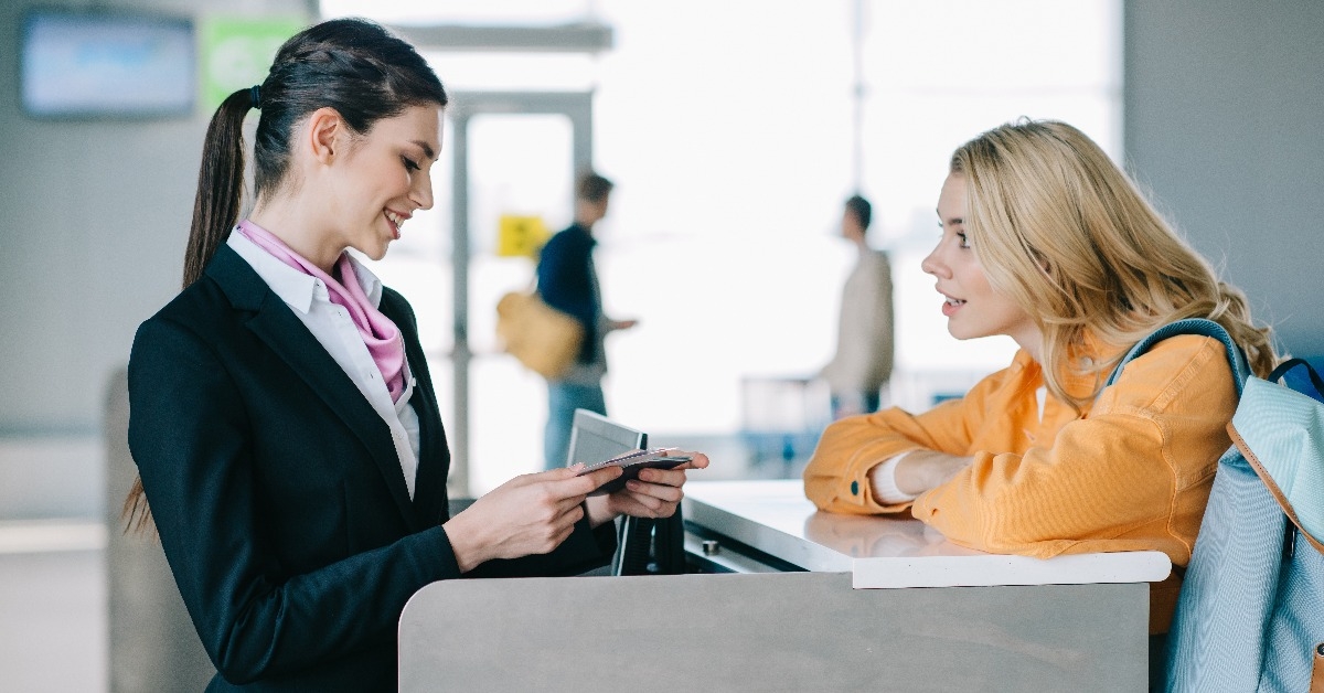 worker checking documents of female traveler at check-in desk