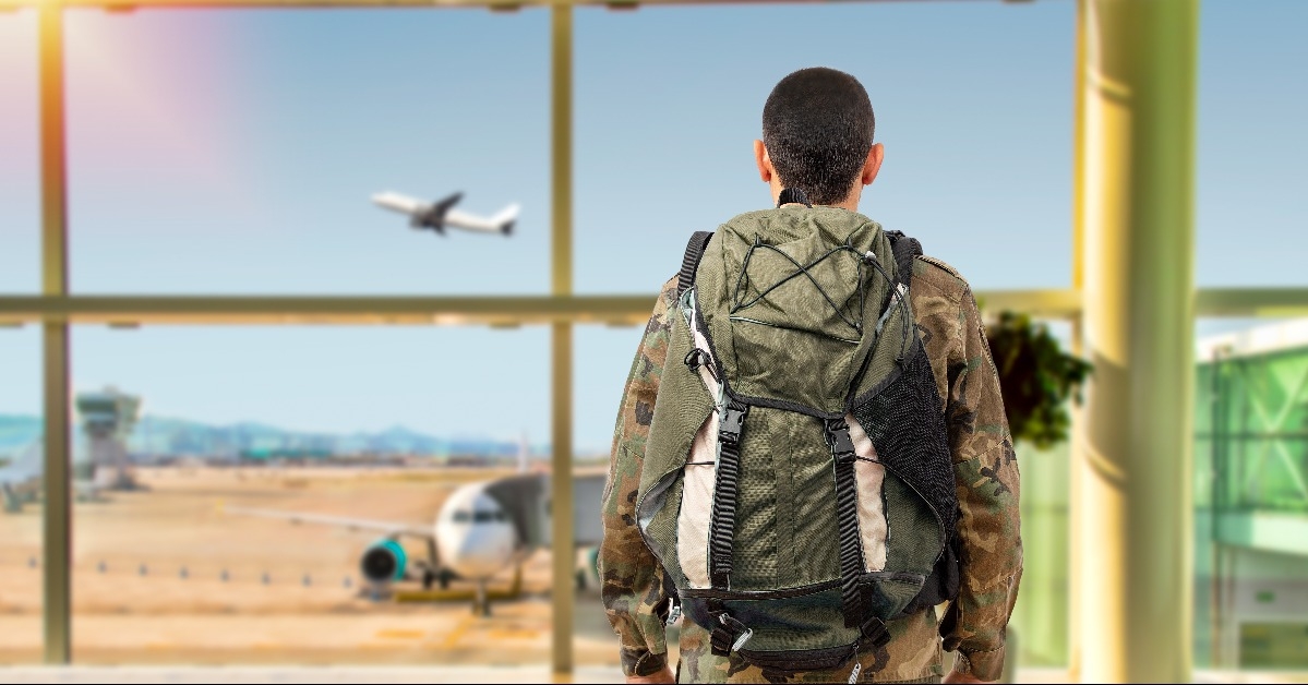 soldier in a military uniform looking through the window at an airport