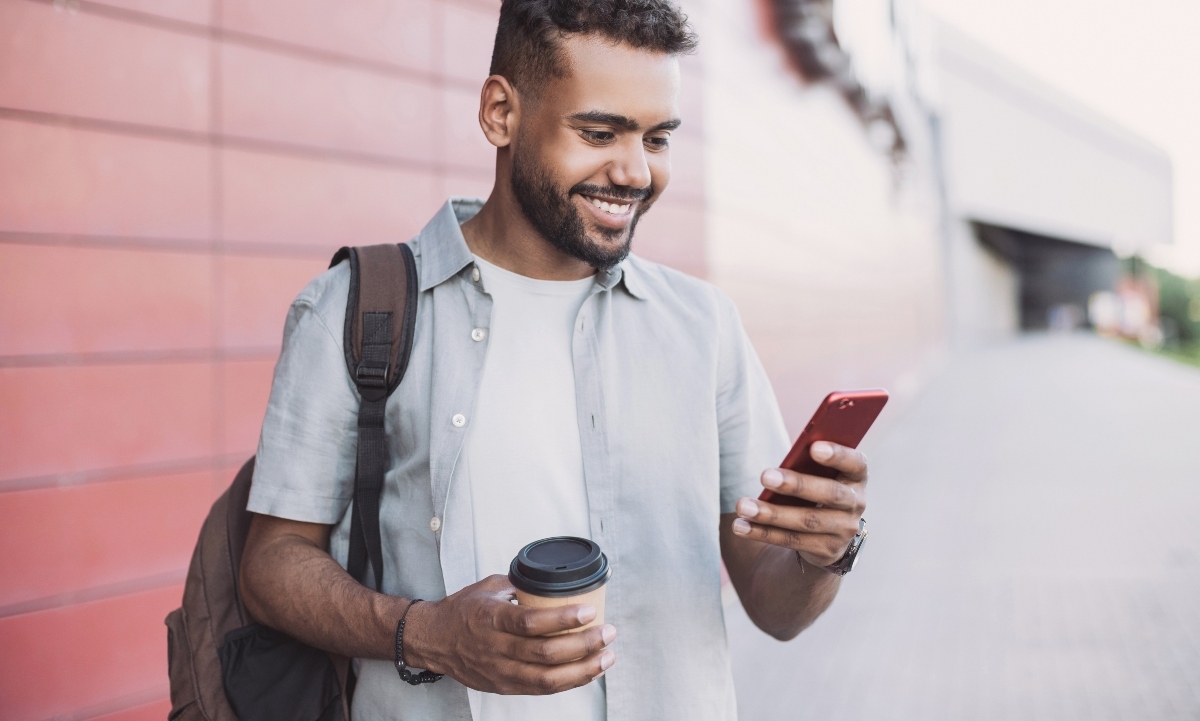 Man holding coffee and looking at phone