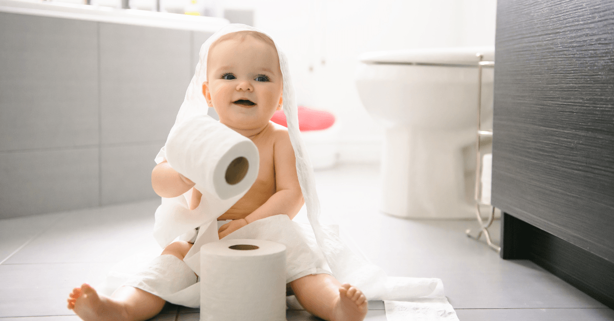 Toddler ripping up toilet paper in bathroom