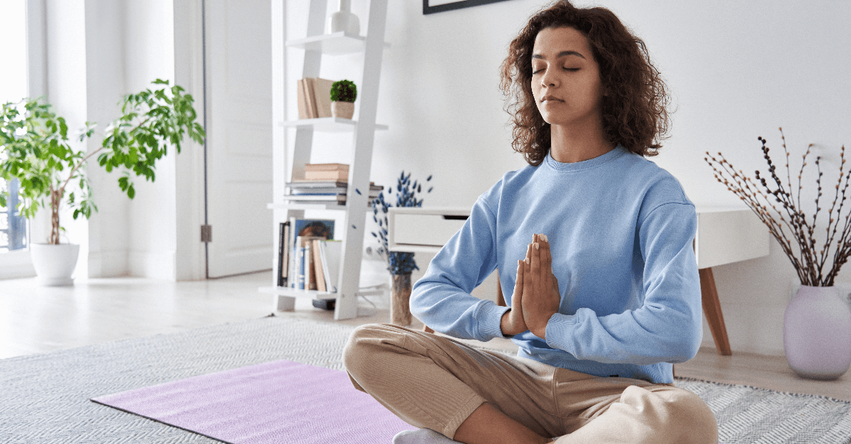 Healthy serene young woman meditating at home with eyes closed
