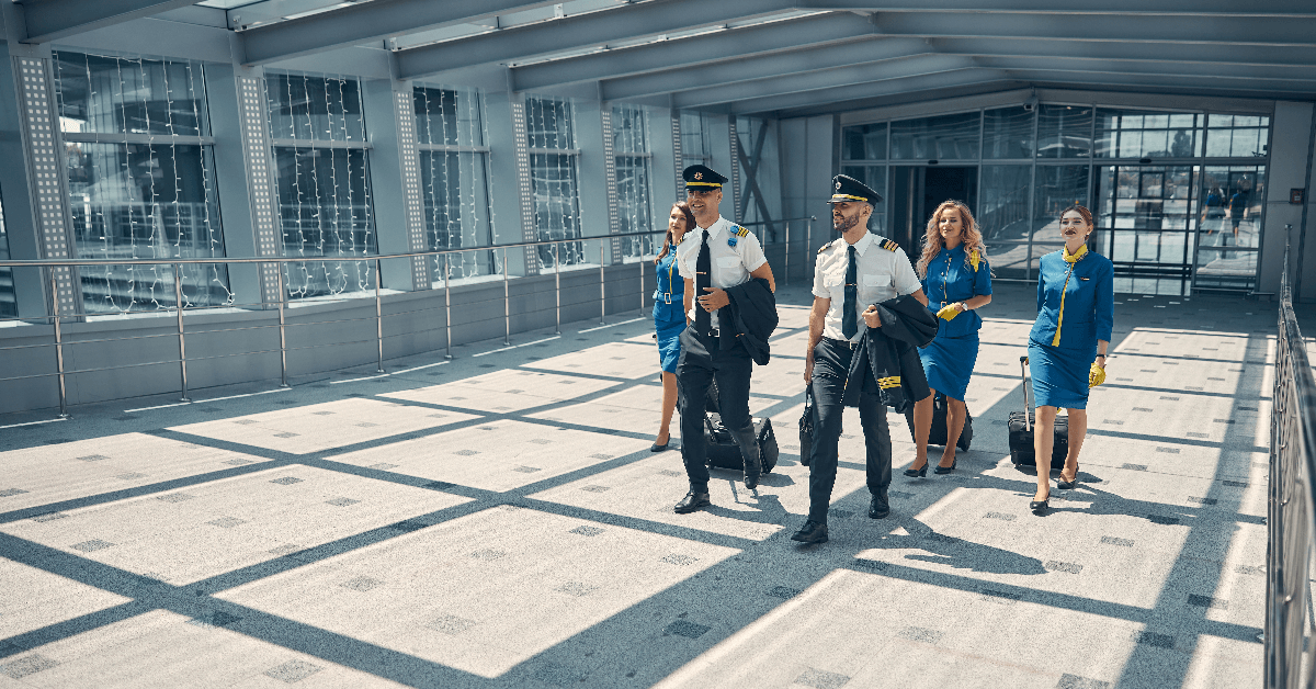 Airline workers with travel suitcases walking in airport terminal