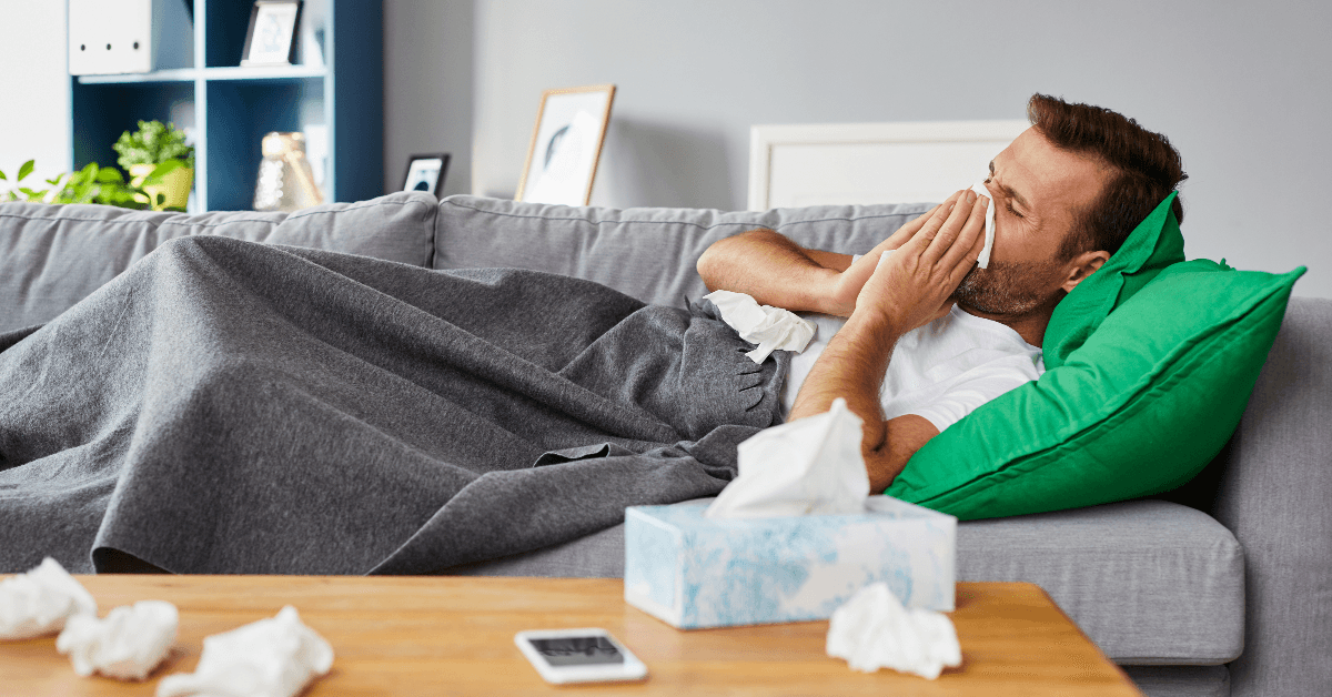 Man laying on a couch sick with a cold