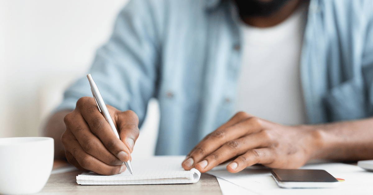 man writing in notebook