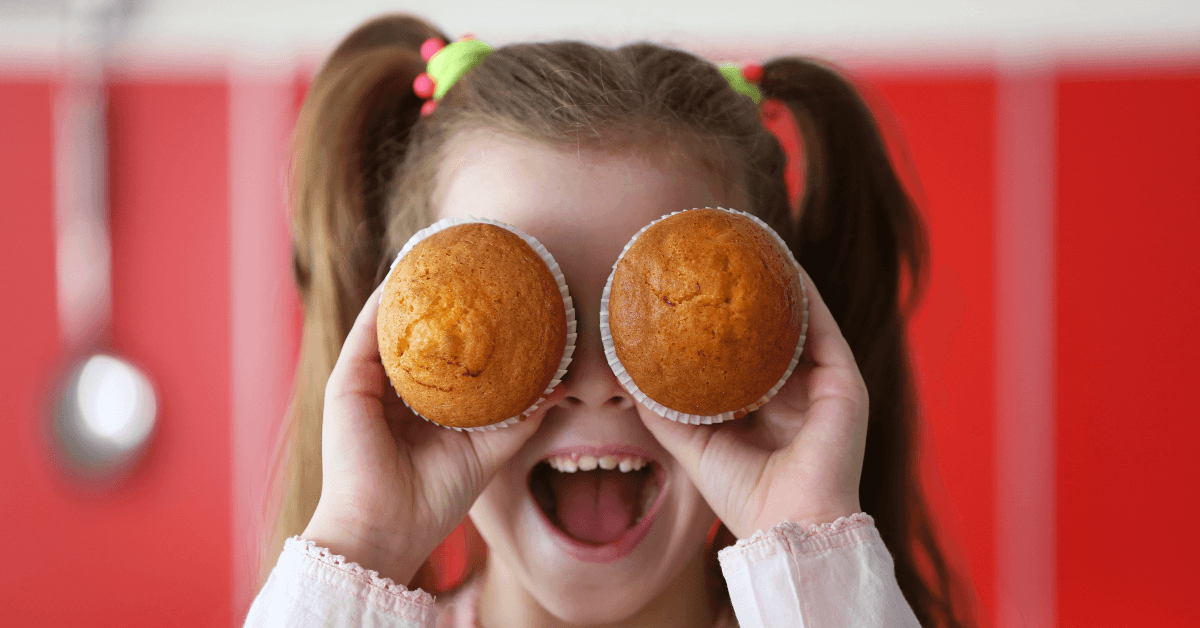 Young girl holding muffins over her eyes