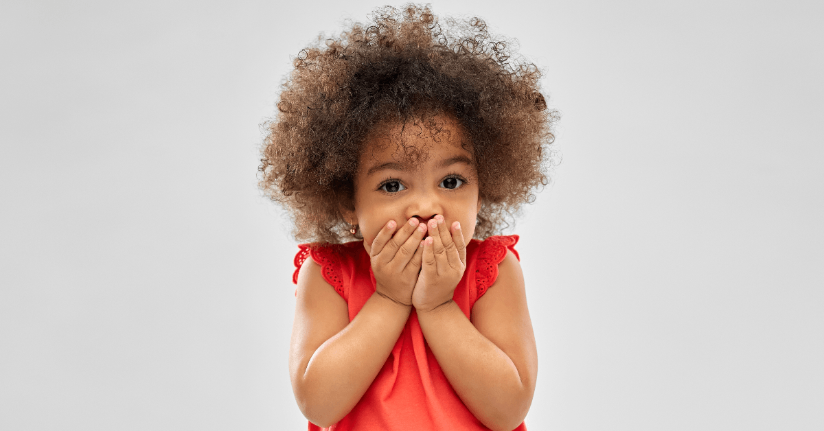 Cute little girl with hands over her mouth