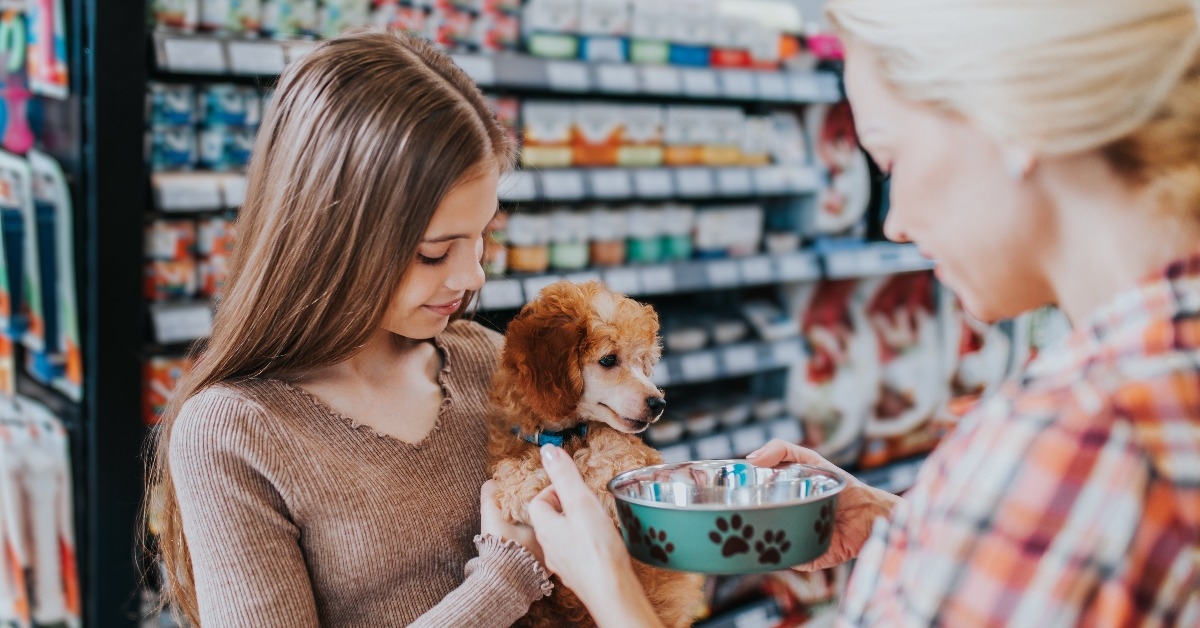 mother and daughter with their poodle puppy in pet shop
