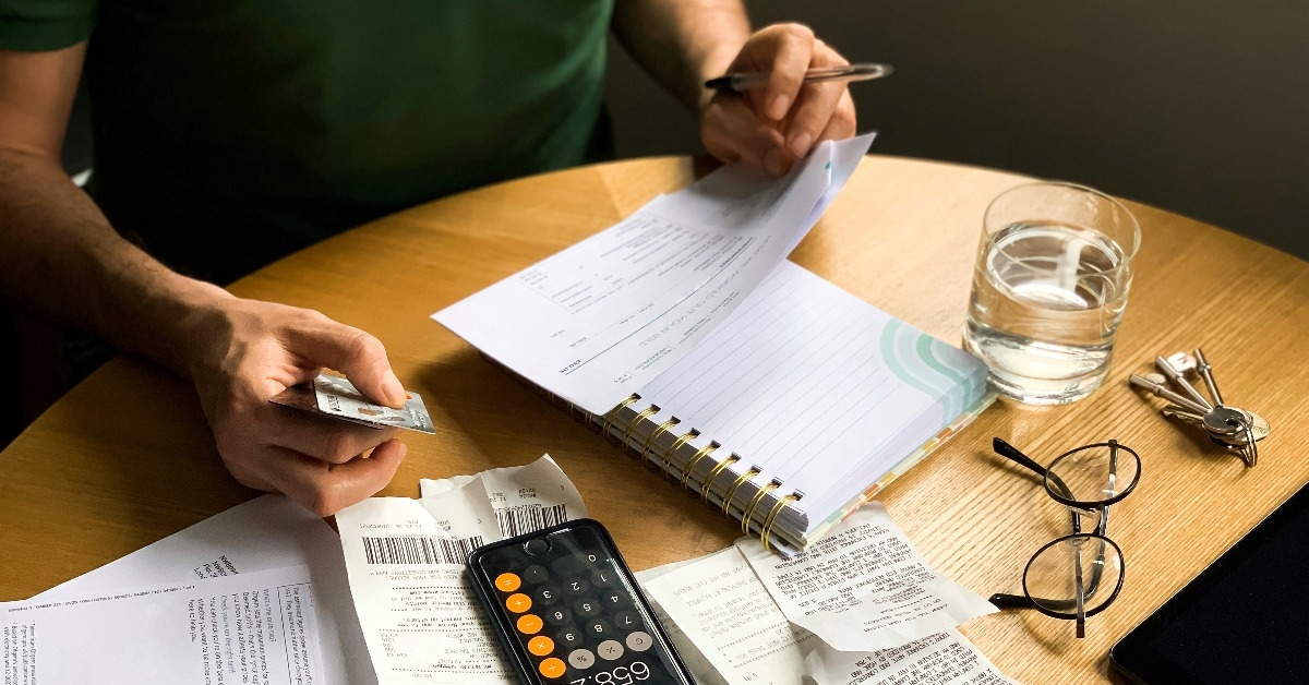 man is making audit of household expenses using calculator and notebook