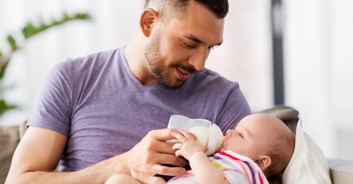 father feeding little daughter with baby formula 