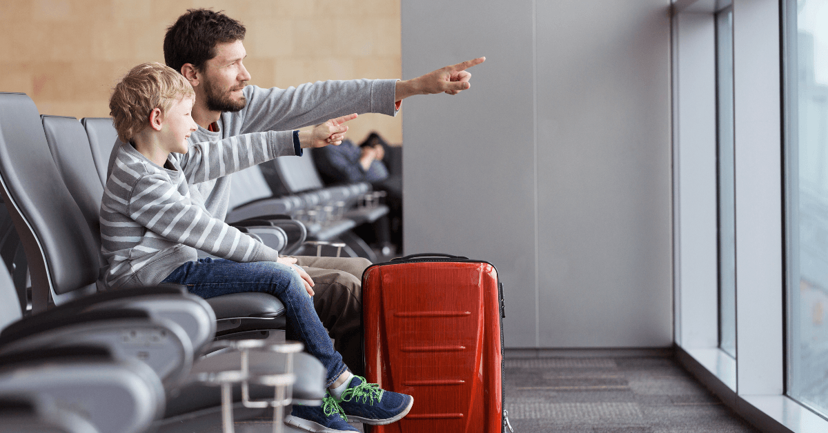 Father and son pointing at planes at airport