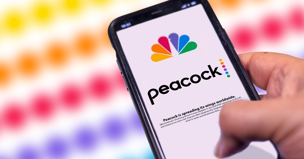 a hand holding a phone with the Peacock Tv mobile app on the screen